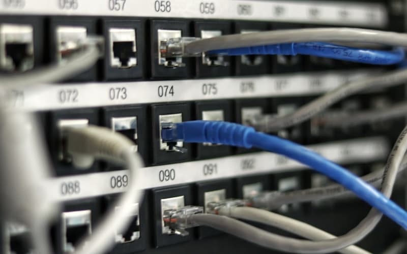 Blue and grey ethernet cables plugged into a numbered patch panel